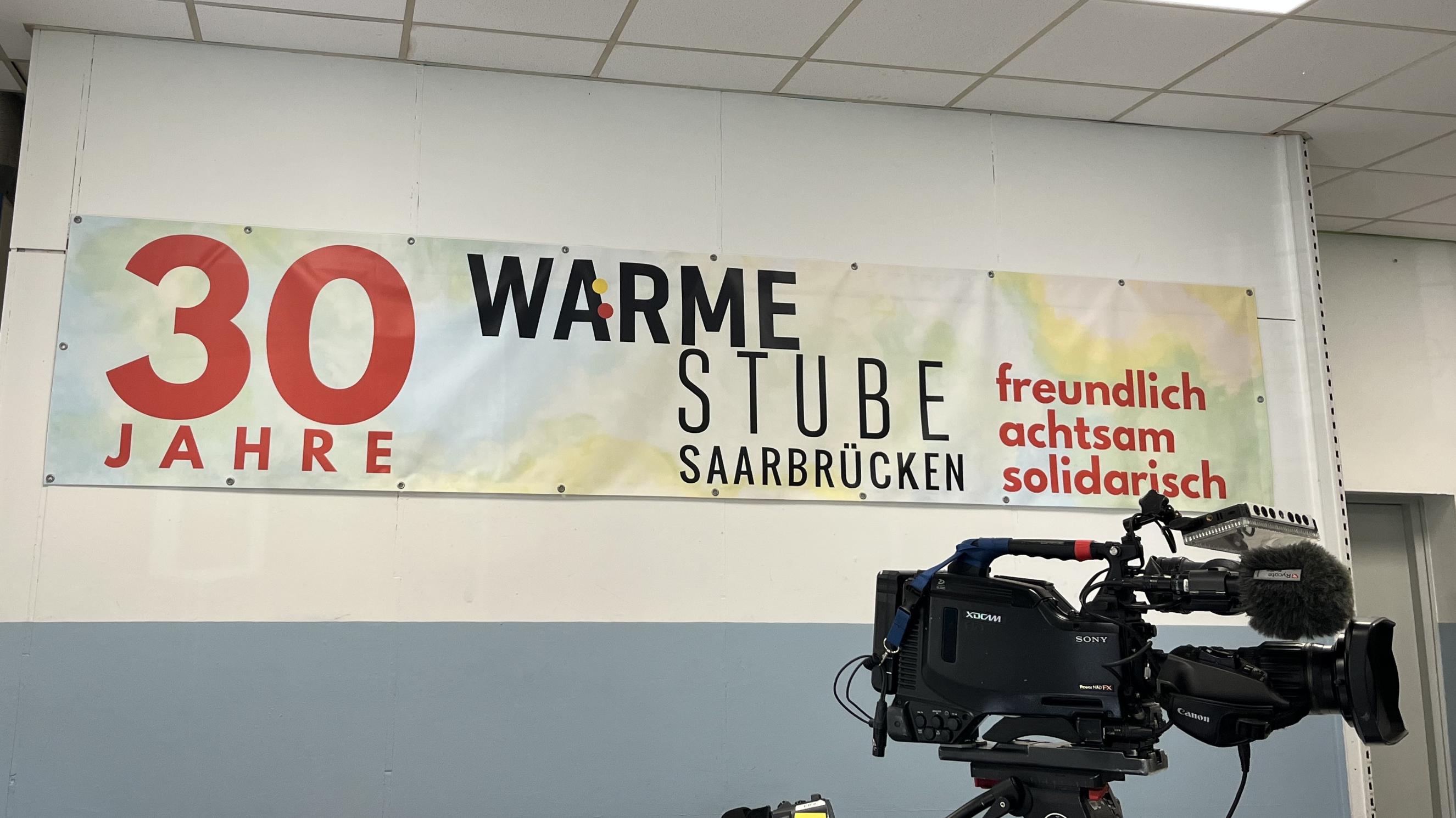 Plakat  '30 Jahre Wärmestube' mit einer Filmkamera im Vordergrund
