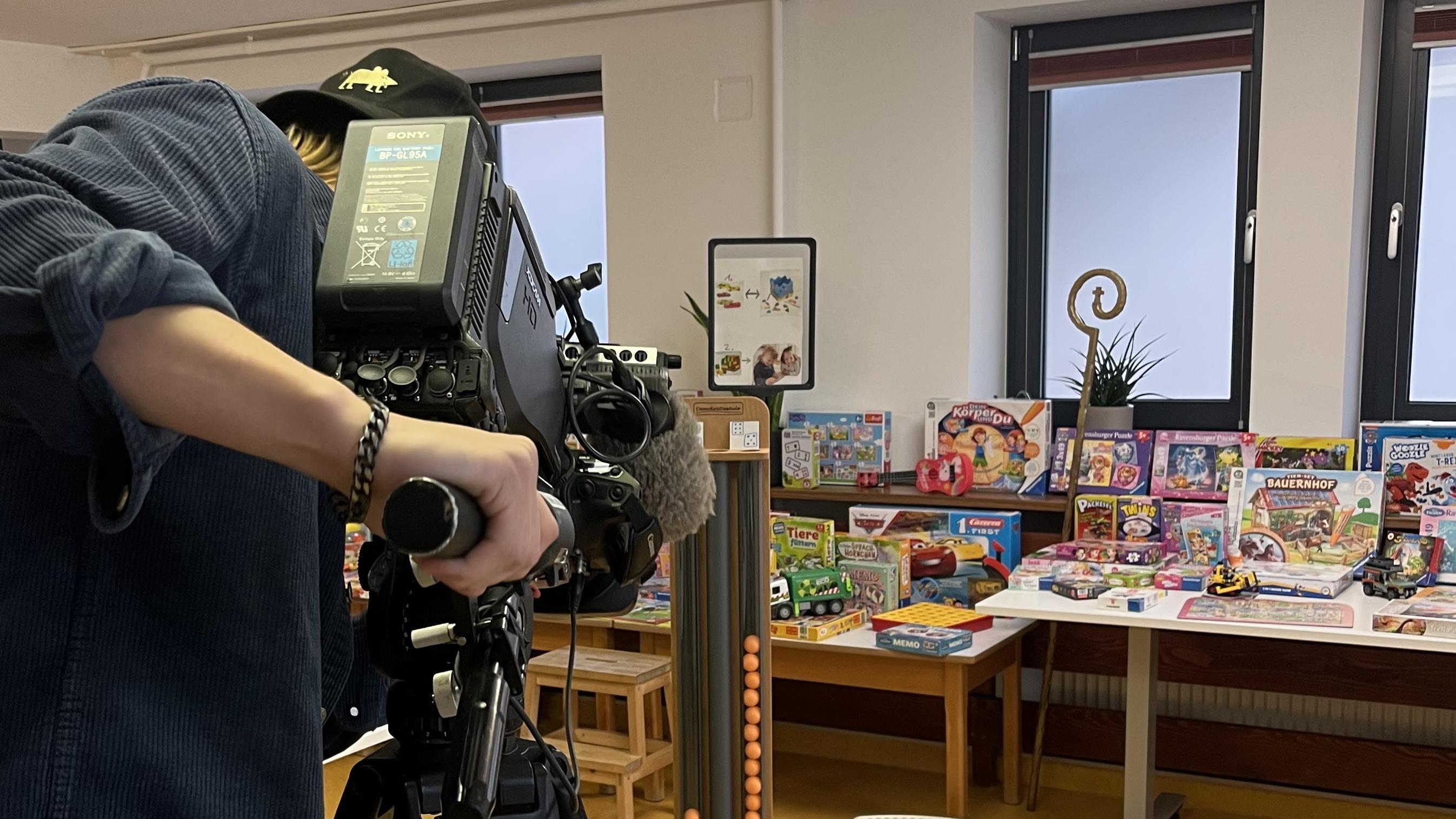Ein Kameramann filmt einen Geschenketisch im Kindergarten