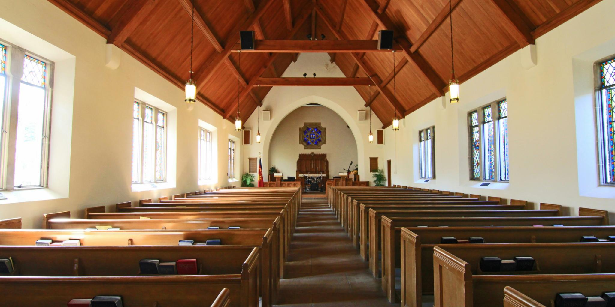 Man blickt in das Innere einer Kirche. Die Wände sind in einem hellen gelb und die Decke ist aus Holz